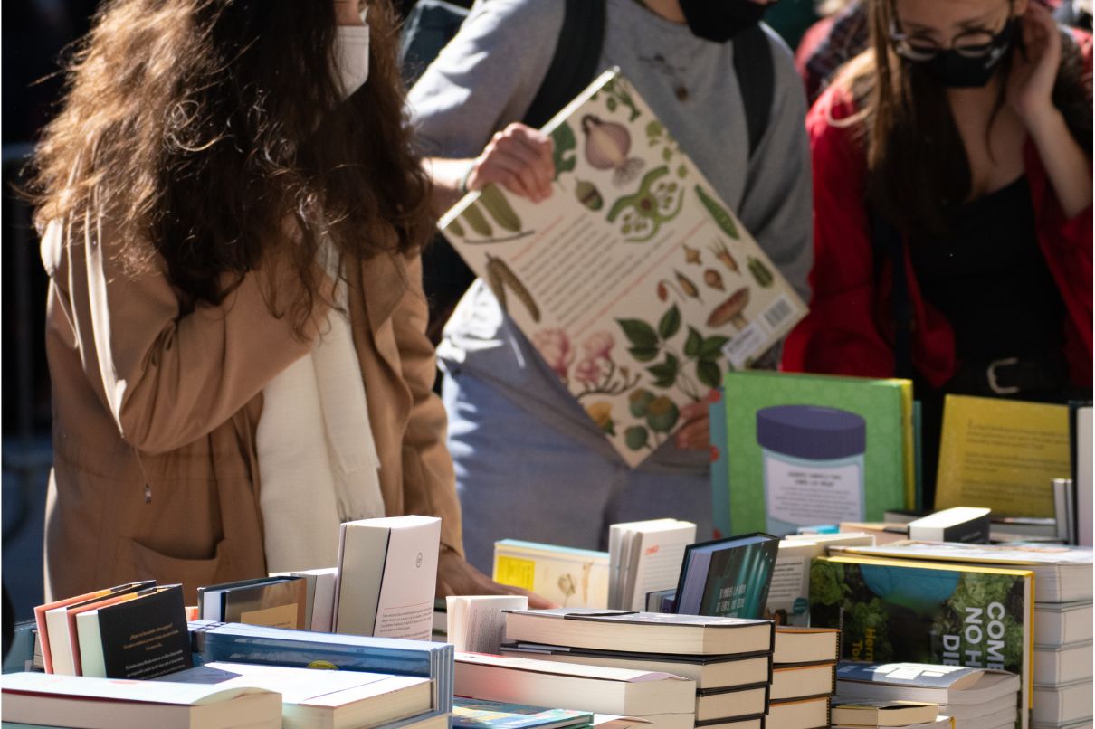 People browsing books at a book fair, exploring various titles and engaging in literary discussions